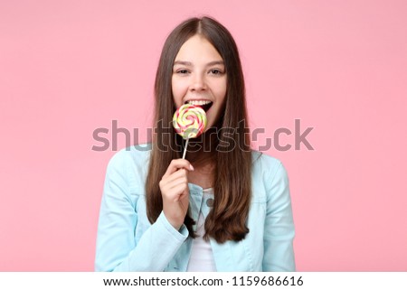 Young girl with lollipop on pink background