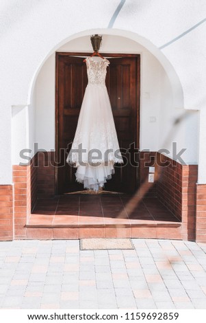Beautiful A-line wedding dress with floral embroidery is hanging outside on the morning of a wedding day