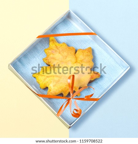 Homemade gingerbread in form of maple leaf in gift box on two-tone background. Minimal autumn food concept