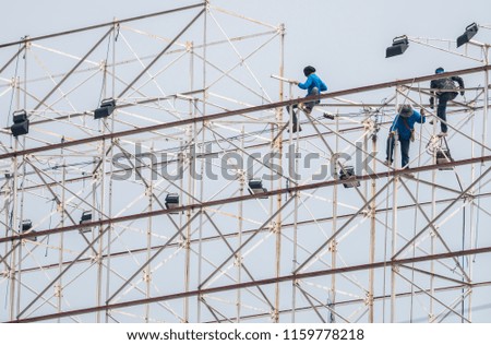 Workers are working on a large billboard structure