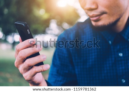 Man blue shirt are using smartphone by internet online,Technology social media everywhere and nature background sunlight