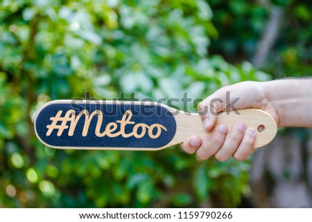 hand holding a wooden black speech bubble with #metoo text on it in green background