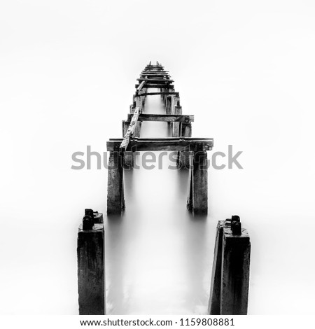 Amazing old abandon wooden jetty in minimalist high key,  black and white fine art photography. (blurry soft focus noise grain visible full resolution)
