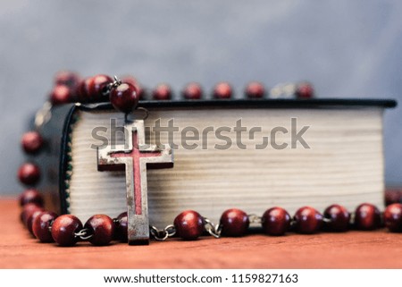 Bible and the crucifix on a red wooden table. Beautiful background.Religion concept