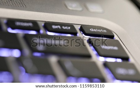close up of  the delete symbol button tab on an illuminated laptop computer key board. The delete key