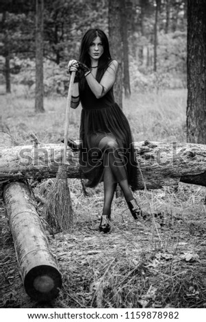 Halloween Witch in a dark forest. Beautiful young woman in witches modern dress . Halloween art design. Dark theme For Halloween Concept