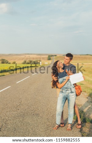 Lovers guy and girl go hitchhiking. In  hands of  sheet with  inscription.  Concept adventures, honeymoon, freedom. Copy space