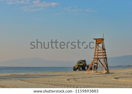 Calm aegean sea at the beach with a safeguard post on a sunny morning with Olympus mountain and clear sky in the background.