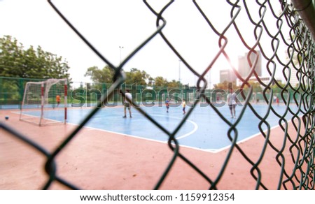Outdoor Futsal Field at the public park in the city.People are playing football.Picture blurred for background.