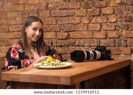 Charming girl with beautiful smile reading good news on mobile phone during rest in restaurant,happy Caucasian female watching her photo on cell telephone while relaxing in restaurant during free time