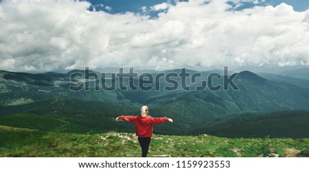 Woman hiker posing in mountauns. Woman enjoying panoramic view of beautiful cloudy sky in mountains, travel and outdoor adventure concept. Carpathians, Ukraine