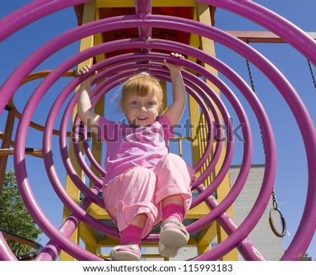 Attractive little girl on outdoor playground equipment