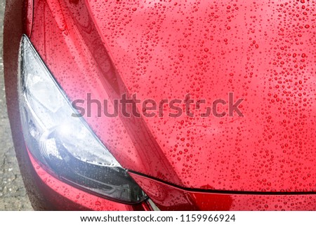 Close up to headlight lamp of red sports car in rain day. Copy space. red sport car wallpaper view.