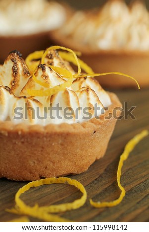 Close up of a lemon tart with lemon zest on a wooden table