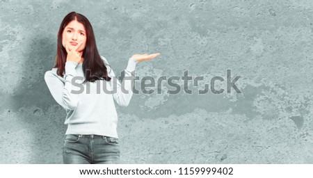 young pretty girl full body with a quizzical and confused look, doubting between different choices or possibilities with a wondering expression, comparing and posing a question.