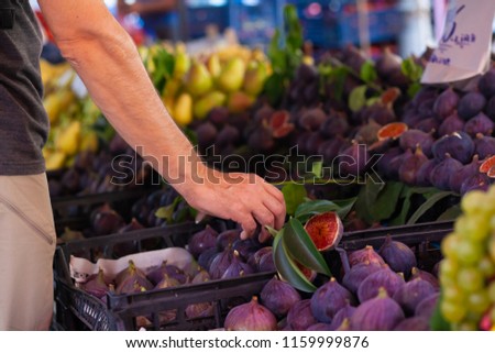 Picture of marketplace with figs fruits. Buyer's and seller's hands on colorful background outdoors