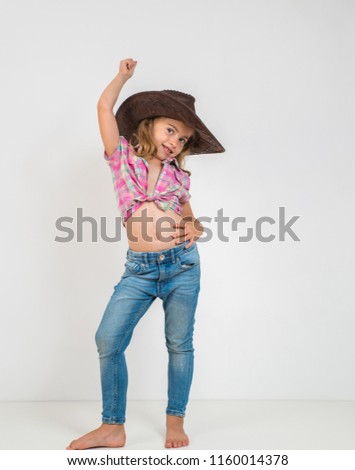 Little girl in cowboy hat and jeans isolated on white background.
