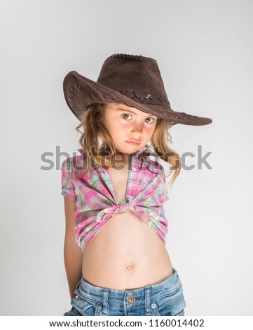 Little girl in cowboy hat and jeans isolated on white background.