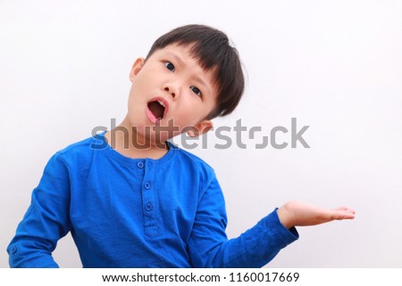 Cute little asian boy in casual wear showing funny expression with his palm facing up, isolated on white background.