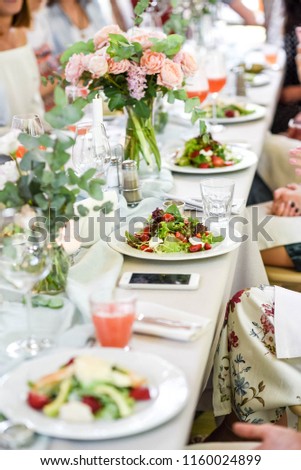 A beautiful summer table for any occasion, holiday, party or wedding. A picture of an elegant female hand. delicious dishes on the table in the restaurant. serving table. 