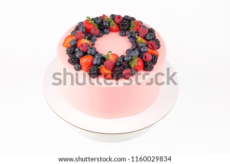 Cake with whipped pink cream, fresh strawberries, blueberries, blackberry and raspberry on white background. Isolated. Picture for a menu or a confectionery catalog.