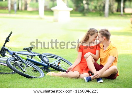 Young couple resting after riding bicycles in park