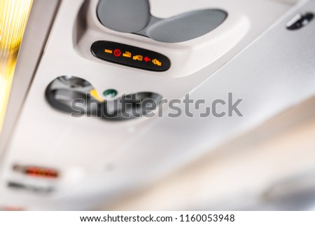 Airplane seat details, abstract aviation background. No smoking sign and seat belt sign on plane. Safety signs and blurred airplane interior 