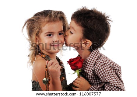 Little boy is  kissing a little girl and they are holding red rose between them. The picture is isolated on white background.