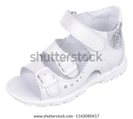 Side upper view of white and silver leather girl sandal with slits and slots, two clasps and one velcro, isolated on white