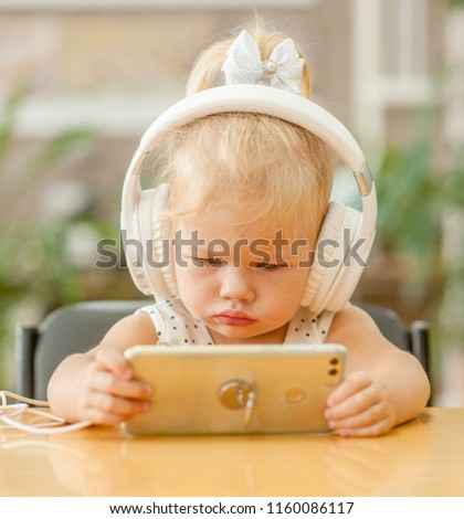 baby girl watching cartoons on phone in headphones