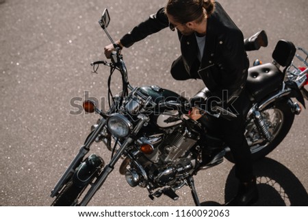 biker sitting on vintage chopper motorcycle on asphalt road