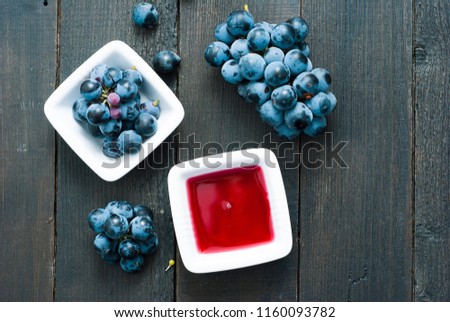 red grape juice in china bowl, black wood table background
