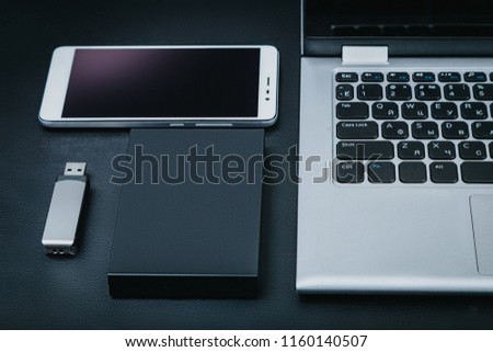 External hdd with the laptop, USB flash drive and smartphone on a black background. The concept of portable business technology