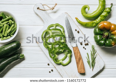 top view of cut green bell pepper on white wooden cutting board