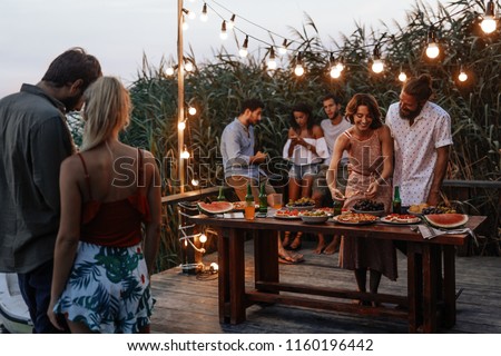 Group of young men and women enjoying summer holiday at outdoor party.