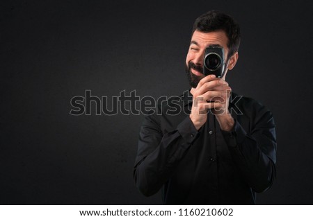 Handsome man with beard filming on black background