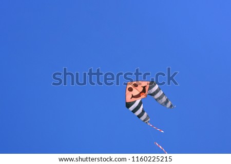Kite with funny cartoon face on blue sky background