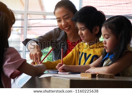 Teachers are teaching drawing on white paper to three children in holiday weekend.