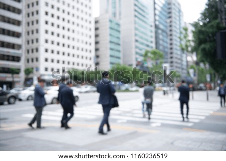 Blurred crowd of anonymous people, commuters on pedestrian waiting for traffic light and crossing the street on zebra crossing in the city, Seoul, Korea