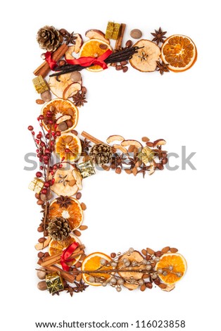 Letter "E" made of Christmas spices, dry orange and apple slices and small gifts. Isolated on white background