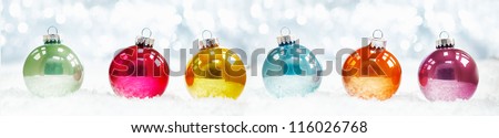 Beautiful shiny Christmas ball banner arranged in a row on fresh white winter snow with a backdrop of sparkling lights
