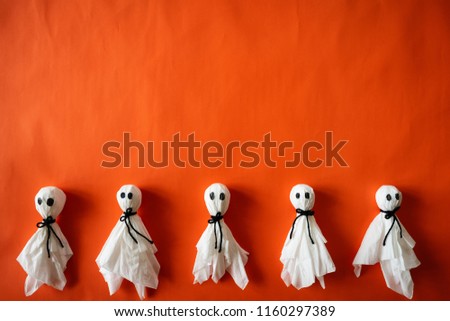 Top view of Halloween crafts, paper ghost on orange paper background with copy space for text. halloween concept.