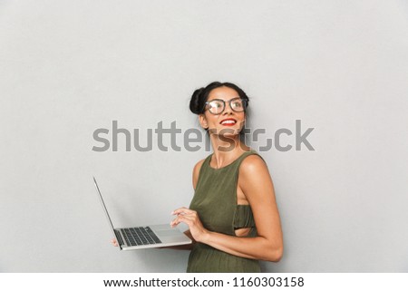 Portrait of a smiling young woman isolated, using laptop computer, looking away