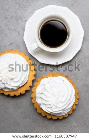 Delicious Dessert. Lemon tartlet tart with meringue and cup of hot coffee on grey stone concrete table background.