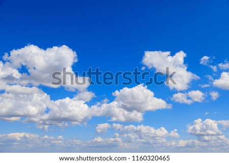 White cumulus summer clouds against a deep blue sky.