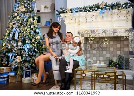 Happy family couple give gifts in the living room, behind the decorated Christmas tree, the light give a cozy atmosphere. New Year and Xmas theme
