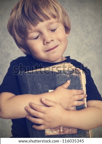Little boy hugging an old book, he is happy