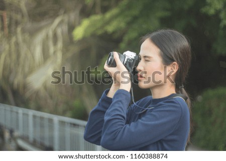 pretty cool young Asian woman with retro film camera or mirrorless camera in modern garden park