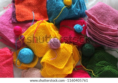 Piles of knitted colorful patches and balls of yarn. 