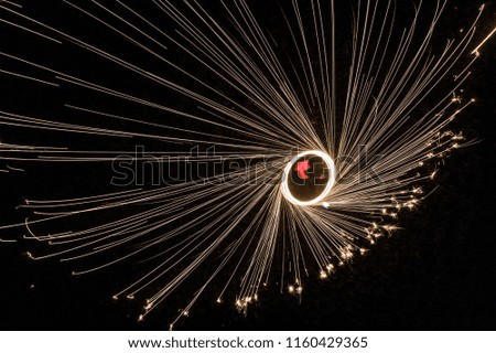 Aerial view of man spinning burning steel wool. Showers of glowing sparks from spinning steel wool. Drone view.
